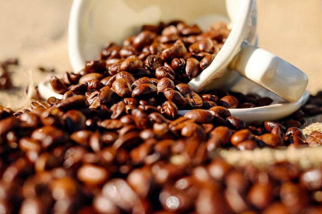 Grãos de café marrons espalhados em mesa por caneca branca